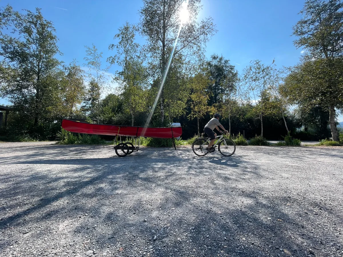 Mit dem Velo fährt Tobias Klein das Kanu in die Badi Egg. Ein Mann mit Velo transportiert ein Kanu auf einem Anhänger.
